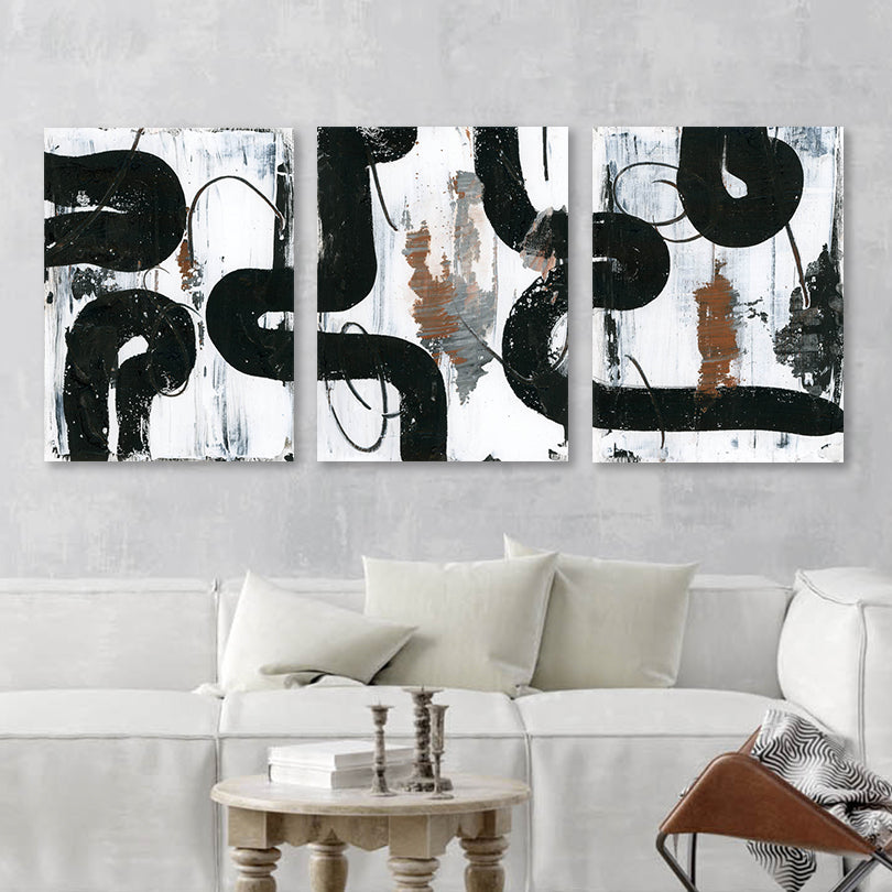 black and white abstract triptych hanging over bohemian couch and coffee table setting